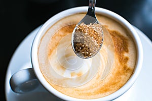 pouring brown sugar in cappuccino