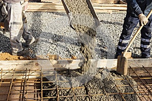 Pouring cement or concrete with a concrete mixer truck, construction site with a reinforced grillage foundation. Workers settle