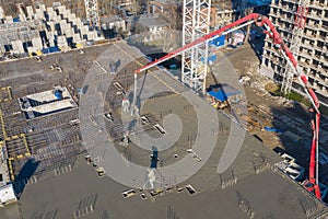 Pouring cement on the floors of residential multi-story building under construction using a concrete pump truck with high boom to