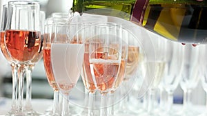 Pouring champagne glass after glass, sparkling rose drink, woman holding bottle and pouring wine