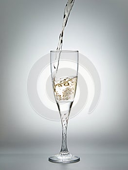 Pouring champagne into glass on gray background