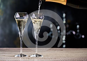 Pouring champagne into glasses. Black and gold background. Copy space for text.
