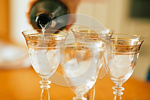 Pouring champagne into a glasses standing on table