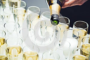 Pouring champagne into a glasses standing on table. Banquet event