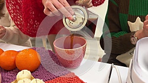 pouring chocolate tea, hot cocoa into a pink cup among a group of girls close-up teapot tangerines and candles Woman