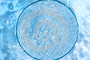 Pouring clean drinking water from blue plastic bottle into glass on blue background