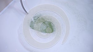 Pouring clear water in bathroom with white foam, close-up view.