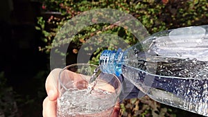 Pouring clear water from a plastic bottle into a glass slow motion
