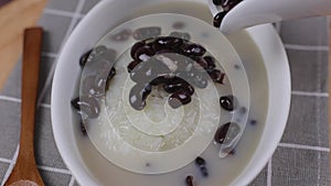 Pouring coconut milk with a black beans on top of Dessert sticky rice