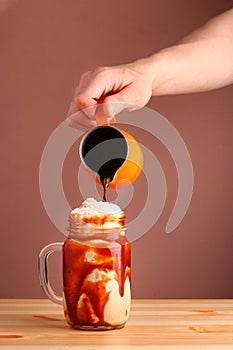 Pouring coffee in milkshake frappuccino . Cold coffee drink frappe frappuccino , with whipped cream and caramel syrup. Salted