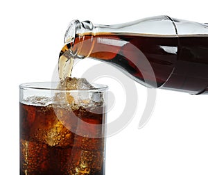 Pouring cola from bottle into glass with ice cubes on white background, closeup. Refreshing soda water