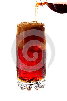Pouring cola into a glass with ice cubes on white background