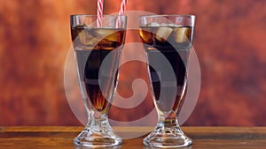 Pouring cola soft drink on ice in tall cafe glasses.