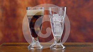 Pouring cola soft drink on ice in tall cafe glasses.