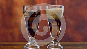 Pouring cola soft drink on ice in tall cafe glasses, time lapse.