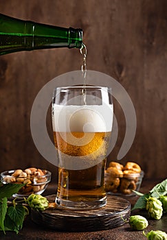 Pouring of cold beer in glass with foam. Beer and snacks