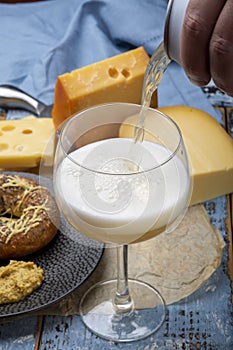 Pouring of cold belgian beer in glass, served in cafe with variety of hard cheeses, tasty european food