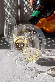 Pouring of cold fino sherry fortified wine in glass in sunlights, andalusian style interior on background