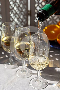 Pouring of cold fino sherry fortified wine in glass in sunlights, andalusian style interior on background