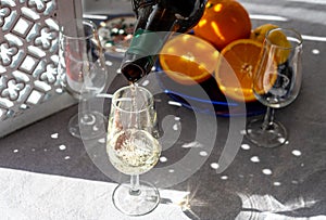 Pouring of cold fino sherry fortified wine in glass in sunlights, andalusian style interior on background