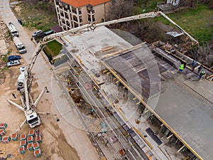 Pouring concrete cement on the roof of residential building under construction using a concrete pump truck machine with high boom