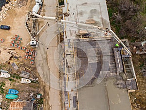 Pouring concrete cement on the roof of residential building under construction using a concrete pump truck machine with high boom