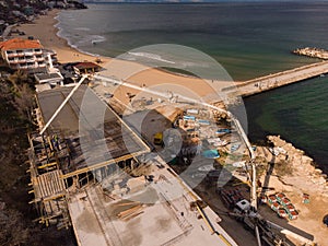 Pouring concrete cement on the roof of residential building under construction using a concrete pump truck machine with high boom