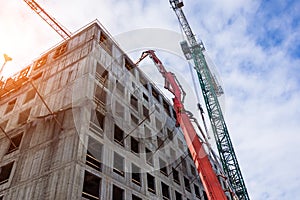 Pouring concrete to the upper floors of a building under construction with the help of an arrow of a concrete mixer truck. View up