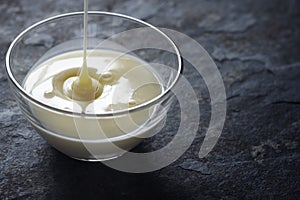 Pouring condensed milk in the glass bowl horizontal