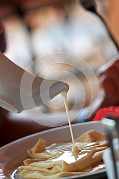 Pouring condensed milk on pancakes