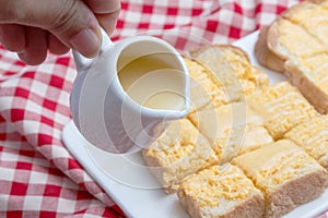 Pouring condensed milk on toasts with butter