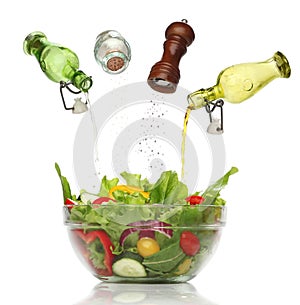 Pouring condiments on a colorful salad.