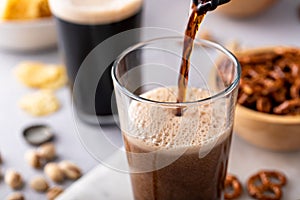 Pouring dark stout beer in a tall glass