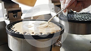 Pouring a dough on waffle iron. Chef step by step preparing Belgian waffles with bananas, strawberries, ice cream, honey