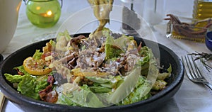Pouring dressing sauce over a Caesar`s salad