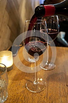 Pouring of dry Italian primitivo red wine in glass in Italian cantina restaurant in Puglia photo