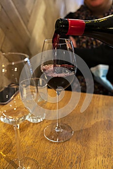 Pouring of dry Italian primitivo red wine in glass in Italian cantina restaurant in Puglia