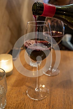 Pouring of dry Italian primitivo red wine in glass in Italian cantina restaurant in Puglia