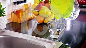 Pouring filtered water into glass from jug in the kitchen