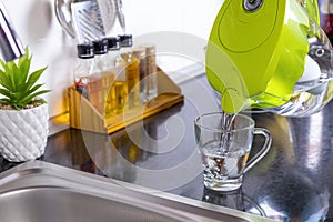 Pouring filtered water into glass from jug in the kitchen photo