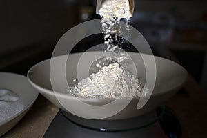 Pouring flour into a deep plate. Dark background