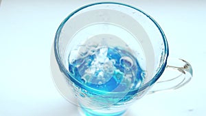 Pouring fresh clean water into a clear blue glass on the table, health and diet concept, isolation on a white background