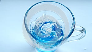 Pouring fresh clean water into a clear blue glass on the table, health and diet concept, isolation on a white background, HD Video