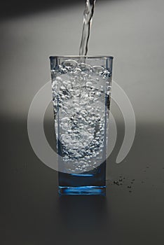 Pouring fresh drink water to blue glass