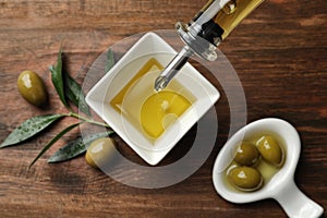 Pouring fresh olive oil into bowl on table,