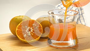 Pouring fresh orange juice into transparent glass.