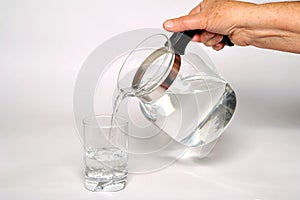 Pouring fresh mineral water from the jug into a glass