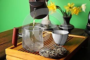 Pouring freshly brewed pu-erh tea into pitcher during traditional ceremony at wooden table