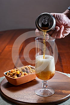 Pouring of German wheat beer is glass and bowl with party mix nuts