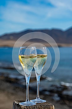 Pouring a glass of champagne on vacation, south of Fuerteventura, Canary islands, blue ocean, mountains